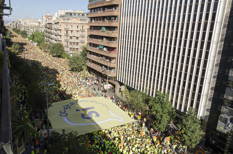 Vista aèria d’una manifestació amb una gran pancarta groga amb la paraula «Sí»