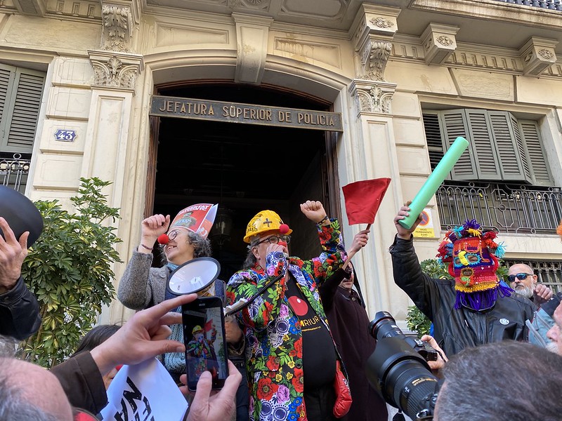 Manifestants davant la Prefectura Superior de Policia de Barcelona, amb un megàfon, màscares i banderes